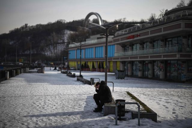 A member of the public sits on the bank of the Dnieper river in the Podil district of Kyiv on February 27, 2026, amid the Russian invasion of Ukraine. (Photo by HENRY NICHOLLS / AFP)