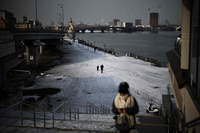 Pedestrians walk along the bank of the Dnieper river in the Podil district of Kyiv on February 27, 2026, amid the Russian invasion of Ukraine. (Photo by HENRY NICHOLLS / AFP)