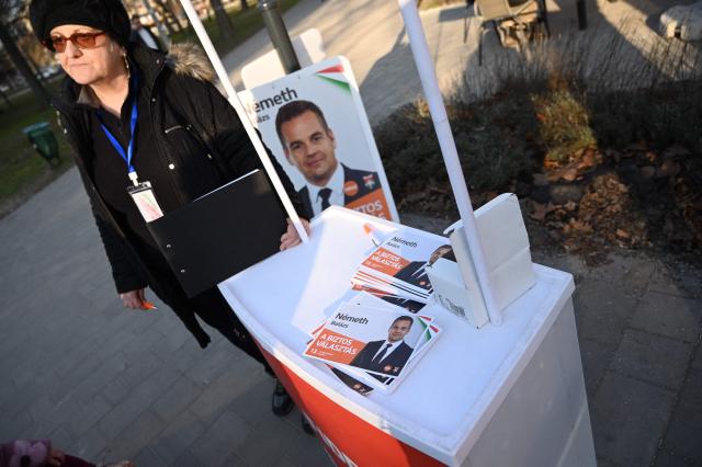 A party activist stands next to postcards showing Hungary's ruling FIDESZ party spokesperson Balazs Nemeth during a campaign in one of Budapest's outer districts on February 27, 2026. (Photo by Attila KISBENEDEK / AFP)