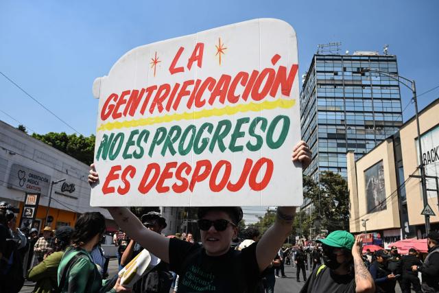 A demonstrator holds a banner reading "Gentrification is not progress, it is dispossession" during a march against gentrification and the upcoming FIFA World Cup, in Mexico City on February 27, 2026. (Photo by Yuri CORTEZ / AFP)