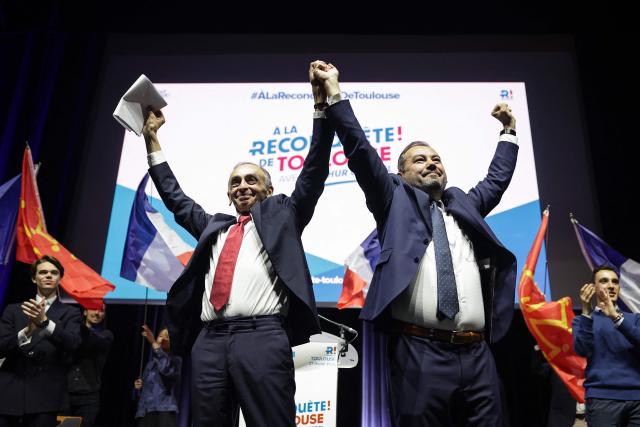 French far-right Reconquete! party leader Eric Zemmour (L) and Reconquete! Toulouse mayoral candidate  Arthur Cottrel (R) greet supporters during a campaign meeting in Toulouse, southwestern France, on February 27, 2026. French voters head to the polls for municipal elections on March 15 and 22, 2026. (Photo by Valentine CHAPUIS / AFP)
