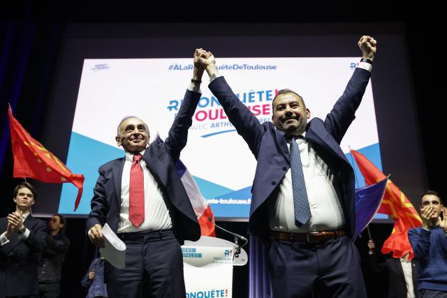 French far-right Reconquete! party leader Eric Zemmour (L) and Reconquete! Toulouse mayoral candidate  Arthur Cottrel (R) greet supporters during a campaign meeting in Toulouse, southwestern France, on February 27, 2026. French voters head to the polls for municipal elections on March 15 and 22, 2026. (Photo by Valentine CHAPUIS / AFP)