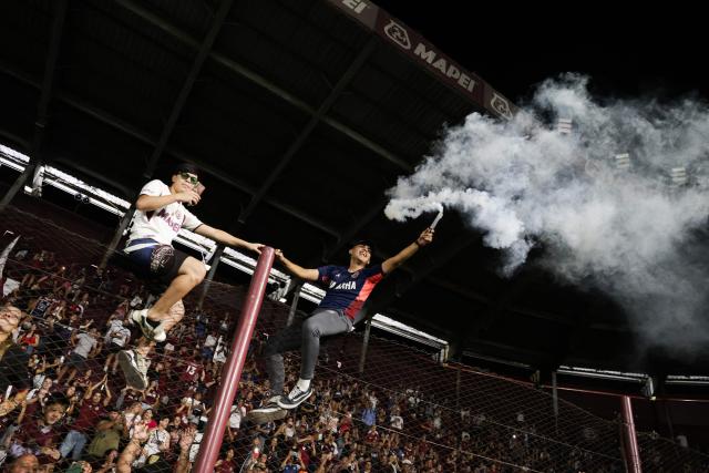 A Lanus fan holds a smoke flare during the team's celebrations, a day after defeating Flamengo at Maracana stadium in Rio de Janeiro to win the Recopa Sudamericana, at Ciudad de Lanus stadium in Lanus, Buenos Aires province on February 27, 2026. (Photo by Francisco Loureiro / AFP)