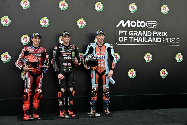 TOPSHOT - Aprilia Racing's Italian rider Marco Bezzecchi (C) celebrates taking pole position next to second-placed Ducati Lenovo Team's Spanish rider Marc Marquez and third-placed Trackhouse MotoGP's Spanish rider Raul Fernandez (R) as they pose for photos after the qualifying session of the MotoGP Thailand Grand Prix at the Buriram International Circuit in Buriram on February 28, 2026. (Photo by Lillian SUWANRUMPHA / AFP)