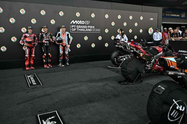 Aprilia Racing's Italian rider Marco Bezzecchi (C) celebrates taking pole position next to second-placed Ducati Lenovo Team's Spanish rider Marc Marquez and third-placed Trackhouse MotoGP's Spanish rider Raul Fernandez (R) as they pose for photos after the qualifying session of the MotoGP Thailand Grand Prix at the Buriram International Circuit in Buriram on February 28, 2026. (Photo by Lillian SUWANRUMPHA / AFP)