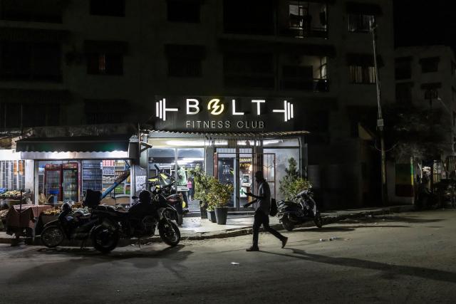 A man walks past the gym where Doudou Sene works during the holy month of Ramadan in Dakar, on February 23, 2026. What started as small workouts in one of the many outdoor gyms that proliferate in Dakar slowly turned into a passion for Doudou Sene. People kept telling him that he had potential in the world of fitness, and in 2019 he began to train seriously. In 2021, he participated in his first powerlifting competition in Dakar and finished first in the under?83 kg category. Soon after, he traveled to The Gambia for another competition, where he finished third. After succeeding as a powerlifter, he decided to switch to bodybuilding, a little?known sport in Senegal with few role models, such as Sidy Pouye, who has managed to build a successful career abroad as a bodybuilder. People dont know much about the sport, but that doesnt stop Doudou from following his passion. During the holy month of Ramadan, training and maintaining a proper diet become challenging. Doudou normally eats five to six meals a day to maintain his gains, but during Ramadan this is reduced to two or three. He prefers to train at the gym where he works right before breaking the fast, and then stays late to help clients with their workouts. Family and religion are his driving forces as he continues pushing himself, even during Ramadan, to achieve his goal of making a living as a bodybuilder and providing for his family. (Photo by PATRICK MEINHARDT / AFP)