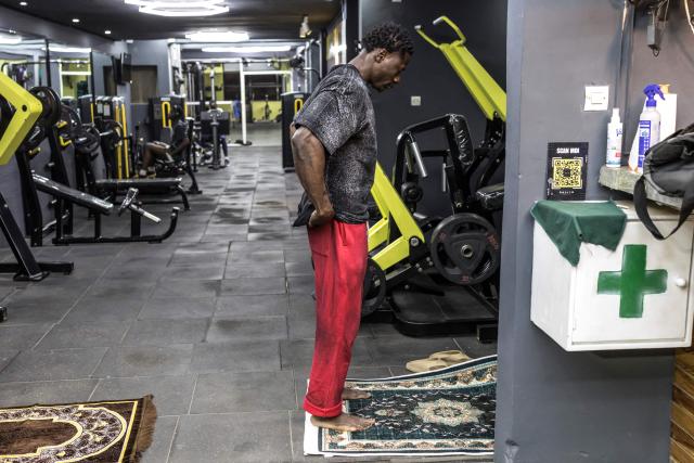 Doudou Sene prays after breaking his fast at a gym during the holy month of Ramadan in Dakar, on February 23, 2026. What started as small workouts in one of the many outdoor gyms that proliferate in Dakar slowly turned into a passion for Doudou Sene. People kept telling him that he had potential in the world of fitness, and in 2019 he began to train seriously. In 2021, he participated in his first powerlifting competition in Dakar and finished first in the under?83 kg category. Soon after, he traveled to The Gambia for another competition, where he finished third. After succeeding as a powerlifter, he decided to switch to bodybuilding, a little?known sport in Senegal with few role models, such as Sidy Pouye, who has managed to build a successful career abroad as a bodybuilder. People dont know much about the sport, but that doesnt stop Doudou from following his passion. During the holy month of Ramadan, training and maintaining a proper diet become challenging. Doudou normally eats five to six meals a day to maintain his gains, but during Ramadan this is reduced to two or three. He prefers to train at the gym where he works right before breaking the fast, and then stays late to help clients with their workouts. Family and religion are his driving forces as he continues pushing himself, even during Ramadan, to achieve his goal of making a living as a bodybuilder and providing for his family. (Photo by PATRICK MEINHARDT / AFP)