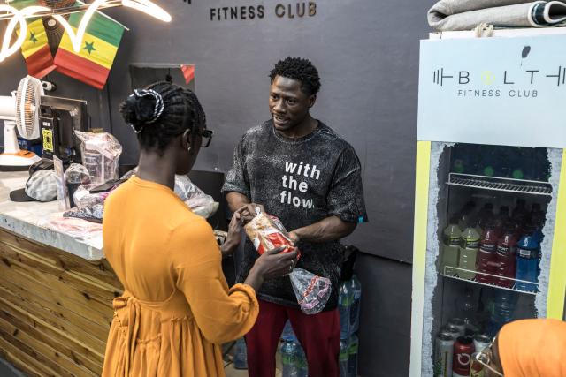 Doudou Sene speaks with a colleague as they get ready to break his fast at a gym during the holy month of Ramadan in Dakar, on February 23, 2026. What started as small workouts in one of the many outdoor gyms that proliferate in Dakar slowly turned into a passion for Doudou Sene. People kept telling him that he had potential in the world of fitness, and in 2019 he began to train seriously. In 2021, he participated in his first powerlifting competition in Dakar and finished first in the under?83 kg category. Soon after, he traveled to The Gambia for another competition, where he finished third. After succeeding as a powerlifter, he decided to switch to bodybuilding, a little?known sport in Senegal with few role models, such as Sidy Pouye, who has managed to build a successful career abroad as a bodybuilder. People dont know much about the sport, but that doesnt stop Doudou from following his passion. During the holy month of Ramadan, training and maintaining a proper diet become challenging. Doudou normally eats five to six meals a day to maintain his gains, but during Ramadan this is reduced to two or three. He prefers to train at the gym where he works right before breaking the fast, and then stays late to help clients with their workouts. Family and religion are his driving forces as he continues pushing himself, even during Ramadan, to achieve his goal of making a living as a bodybuilder and providing for his family. (Photo by PATRICK MEINHARDT / AFP)