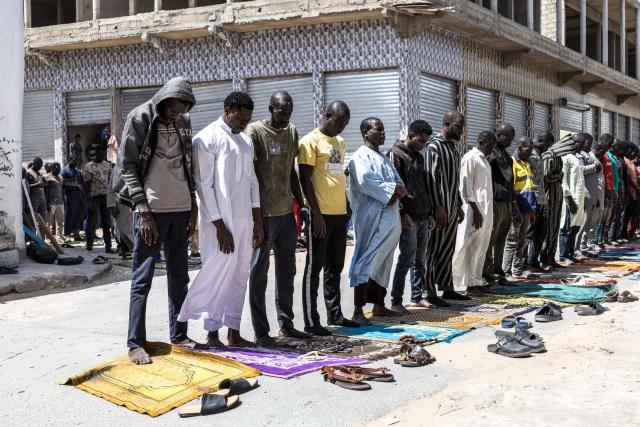TOPSHOT - Doudou Sene (2L) prays with fellow Muslims during the Friday prayer of the holy month of Ramadan in Dakar, on February 27, 2026. What started as small workouts in one of the many outdoor gyms that proliferate in Dakar slowly turned into a passion for Doudou Sene. People kept telling him that he had potential in the world of fitness, and in 2019 he began to train seriously. In 2021, he participated in his first powerlifting competition in Dakar and finished first in the under?83 kg category. Soon after, he traveled to The Gambia for another competition, where he finished third. After succeeding as a powerlifter, he decided to switch to bodybuilding, a little?known sport in Senegal with few role models, such as Sidy Pouye, who has managed to build a successful career abroad as a bodybuilder. People dont know much about the sport, but that doesnt stop Doudou from following his passion. During the holy month of Ramadan, training and maintaining a proper diet become challenging. Doudou normally eats five to six meals a day to maintain his gains, but during Ramadan this is reduced to two or three. He prefers to train at the gym where he works right before breaking the fast, and then stays late to help clients with their workouts. Family and religion are his driving forces as he continues pushing himself, even during Ramadan, to achieve his goal of making a living as a bodybuilder and providing for his family. (Photo by PATRICK MEINHARDT / AFP)