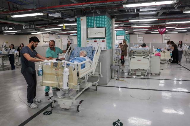 Hospital staff move patients in a parking lot at Sourasky Medical Center for safety after sirens sounded in Tel Aviv on February 28, 2026, following the announcement that Israel had launched a “preemptive strike” on Iran. President Donald Trump urged Iranians on February 28 to take over their government as US forces began a large-scale attack on the country's military. (Photo by Jack GUEZ / AFP)