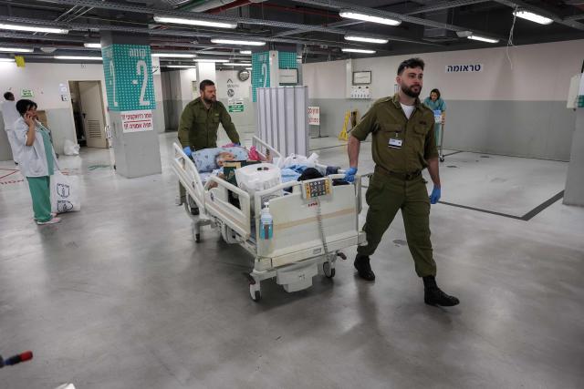 Memebers of the Israeli security personnel move a patient in a parking lot at Sourasky Medical Center for safety after sirens sounded in Tel Aviv on February 28, 2026, following the announcement that Israel had launched a “preemptive strike” on Iran. President Donald Trump urged Iranians on February 28 to take over their government as US forces began a large-scale attack on the country's military. (Photo by Jack GUEZ / AFP)