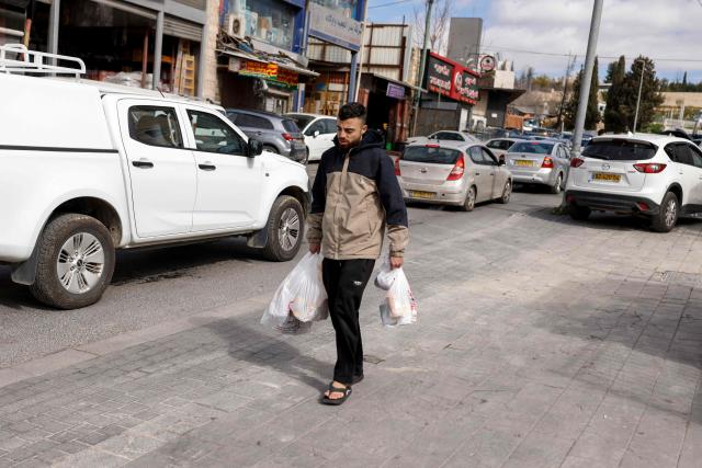 A man walks carrying groceries in Jerusalem on February 28, 2026. Israeli Prime Minister Benjamin Netanyahu said Iran must not be allowed to gain nuclear arms and urged Israelis to "stand together" after Israel and the United States launched strikes against the Islamic republic on February 28. (Photo by John Wessels / AFP)