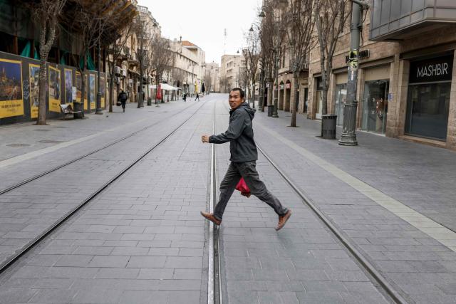 TOPSHOT - A man runs across a street as sirens sound in Jerusalem on February 28, 2026. The Israeli military said its strikes on Iran, in coordination with the United States, targeted dozens of military sites and followed months of joint planning between the allies. (Photo by John Wessels / AFP)