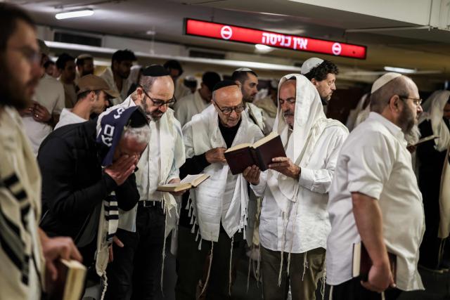 TOPSHOT - Jews pray as they take shelter in Tel Aviv on February 28, 2026. The Israeli military said its strikes on Iran, in coordination with the United States, targeted dozens of military sites and followed months of joint planning between the allies. (Photo by Ilia YEFIMOVICH / AFP)