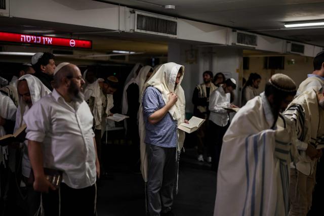 Jews pray as they take shelter in Tel Aviv on February 28, 2026. The Israeli military said its strikes on Iran, in coordination with the United States, targeted dozens of military sites and followed months of joint planning between the allies. (Photo by Jack GUEZ / AFP)