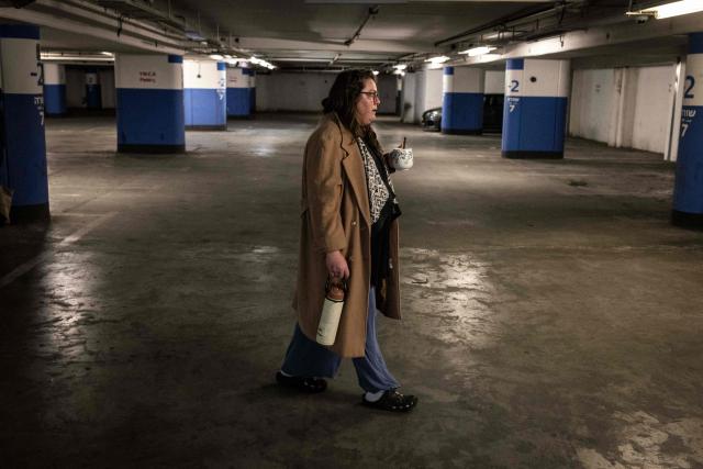 A woman drinks coffee as she takes shelter in a underground parking as sirens sound in Jerusalem on February 28, 2026. The United States and Israel launched a wave of strikes against targets in Iranian cities on February 28, triggering explosions and columns of smoke in the capital Tehran. Iran responded by launching retaliatory missile attacks, according to the Israeli military, as US diplomats in the Gulf and Israeli civilians were ordered to seek shelter. (Photo by John WESSELS / AFP)