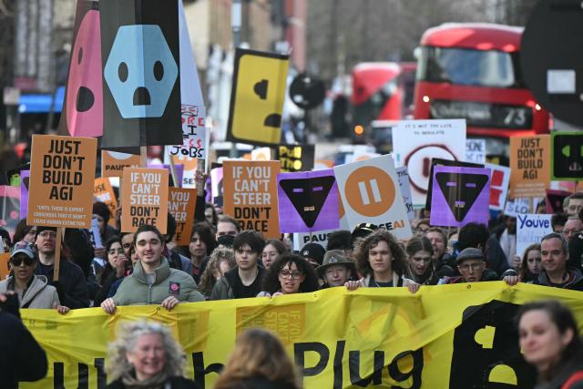 Protesters march behind a large banner at a protest organized by PauseAI UK and other groups concerned in controlling the development of advanced Artificial Intelligence systems, in London on February 28, 2026. (Photo by JUSTIN TALLIS / AFP)