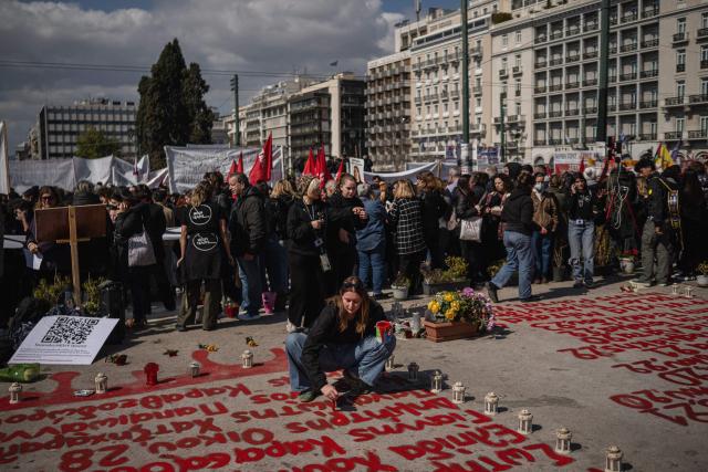 A woman writes the names of victims on the ground during a demonstration outside the Greek parliament, in Athens, on February 28, 2026, marking the third anniversary of the Tempi train crash that killed 57 people in 2023. Thousands of people across Greece will demonstrate on February 28, 2026, in solidarity with victims of the country's worst train tragedy, which claimed 57 lives in 2023 and rattled the government of Prime Minister Kyriakos Mitsotakis. (Photo by Angelos TZORTZINIS / AFP)