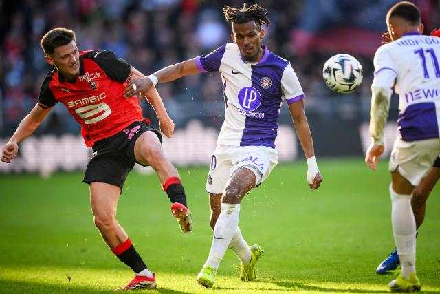 Toulouse's French forward #10 Yann Gboho (C) controls the ball next to Rennes' French defender #26 Quentin Merlin (L) during the French L1 football match between Stade Rennais and Toulouse FC at the Roazhon Park stadium in Rennes, western France on February 28, 2026. (Photo by Loic VENANCE / AFP)
