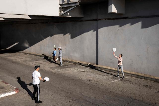 TOPSHOT - People play racketball outside an underground parking garage used as a shelter in Tel Aviv on February 28, 2026. The United States and Israel launched strikes against Iran on February 28, with Israel's public broadcaster reporting that the Iranian supreme leader had been targeted, as the Islamic republic retaliated with barrages of missiles at Gulf states and Israel. (Photo by JOHN WESSELS / AFP)