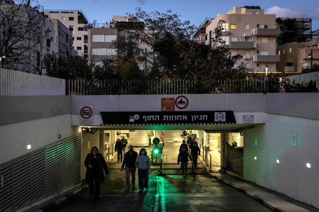 People leave an underground parking garage used as a shelter in Tel Aviv on February 28, 2026. The United States and Israel launched strikes against Iran on February 28, with Israel's public broadcaster reporting that the Iranian supreme leader had been targeted, as the Islamic republic retaliated with barrages of missiles at Gulf states and Israel. (Photo by JOHN WESSELS / AFP)