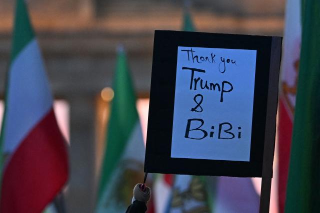 Protestors hold a placard which reads "Thank you Trump and Bibi (Benjamin Netanyahu)" during a demonstration "Freedom for Iran" in front of the Brandenburger Gate in Berlin, on February 28, 2026. The United States and Israel launched strikes against Iran on February 28, sparking fears of regional war with explosions reported across the Middle East as the Islamic republic retaliated with barrages of missiles. (Photo by RALF HIRSCHBERGER / AFP)