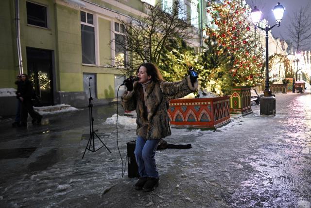 A busker sings on a snow covered street in central Moscow on February 28, 2026. (Photo by HECTOR RETAMAL / AFP)