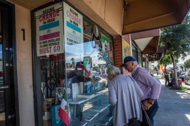 A couple look at the books in the showroom of a Iranian bookstore with posters against the Ayatollahs in the Persian Square at the West LA neighborhood with in Los Angeles, California on February 28, 2026. The US and Israel launched an attack of unprecedented scale against Iran on Saturday, reportedly killing more than 200 people, with Tehran launching a retaliatory missile barrage that sent people running for cover across the Middle East. (Photo by Apu GOMES / AFP)