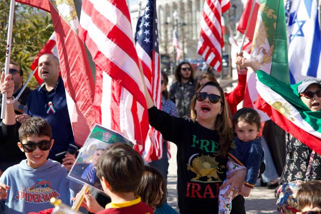 A group of Iranian Americans gather at the World War I Memorial in Washington, DC, during a rally expressing support for potential US and Israeli military action against Iran’s Islamic Republic government on February 29, 2026 in Washington, DC. The US and Israel launched an attack of unprecedented scale against Iran on Saturday, reportedly killing more than 200 people, with Tehran launching a retaliatory missile barrage that sent people running for cover across the Middle East. (Photo by Amid FARAHI / AFP)