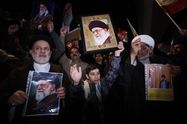 Iraqi Shiites hold portraits of Iran's Supreme Leader Ayatollah Ali Khamenei during a protest against US and Israeli attacks on  Iran at a bridge leading to  Green Zone where the US embassy is located, in Baghdad on February 28, 2026. Several hundred people protested against the US-Israeli strikes on Iran near the US embassy in Baghdad on Saturday, AFP journalists said. (Photo by AHMAD AL-RUBAYE / AFP)