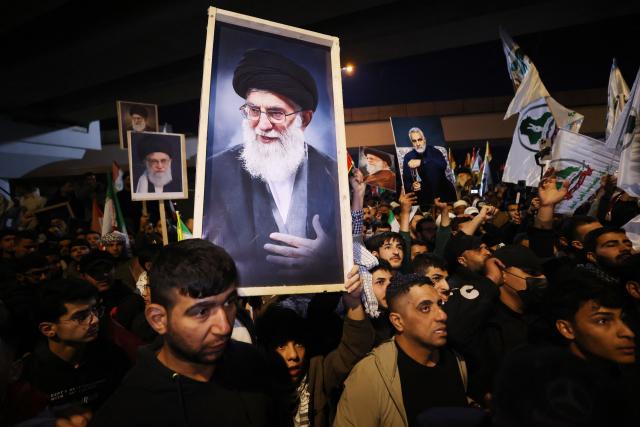 Iraqi Shiites carry a portrait  of Iran's Supreme Leader Ayatollah Ali Khamenei during a protest against US and Israeli attacks on Iran at a bridge leading to  Green Zone where the US embassy is located, in Baghdad on February 28, 2026. Several hundred people protested against the US-Israeli strikes on Iran near the US embassy in Baghdad on Saturday, AFP journalists said. (Photo by AHMAD AL-RUBAYE / AFP)