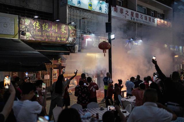 People film fireworks outside a shop during the celebrations of the Chinese New Year, marking the beginning of the Year of the Fire Horse in Cyrildene, Johannesburg on February 28, 2026. (Photo by ILARIA FINIZIO / AFP)