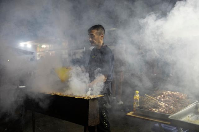 A vendor grills food at a stall during the celebrations of the Chinese New Year, marking the beginning of the Year of the Fire Horse in Cyrildene, Johannesburg on February 28, 2026. (Photo by ILARIA FINIZIO / AFP)