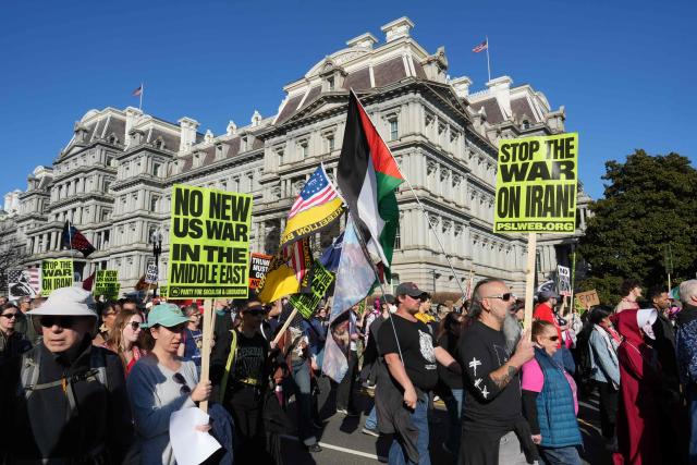 People wave Iranian flags and signs condemning the war on Iran as they march past the Eisenhower Executive Building during a protest in Washington, DC, on February 28, 2026. The United States and Israel launched what the latter called a "decisive and unprecedented" campaign against Iran, which retaliated with a barrage of missiles that sent residents running for cover on Saturday in cities across the Middle East. (Photo by Ken Cedeno / AFP)