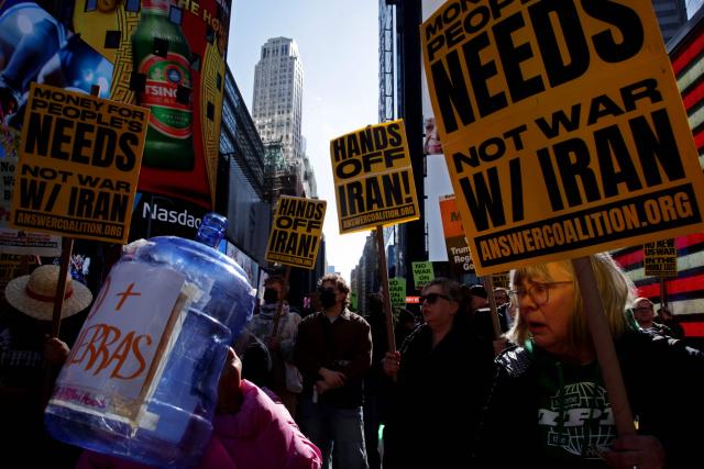 People hoist signs during a "Stop the War on Iran" protest in Times Square in New York City on February 28, 2026. The US and Israel launched an attack of unprecedented scale against Iran earlier on Saturday. (Photo by Leonardo MUNOZ / AFP)