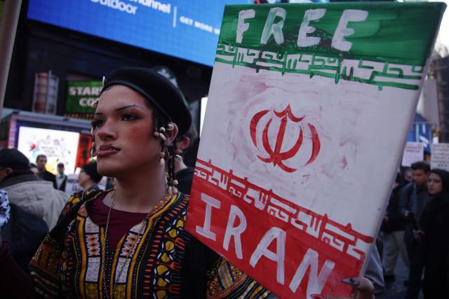People hoist signs during a "Stop the War on Iran" protest in Times Square in New York City on February 28, 2026. The US and Israel launched an attack of unprecedented scale against Iran earlier on Saturday. (Photo by Leonardo MUNOZ / AFP)