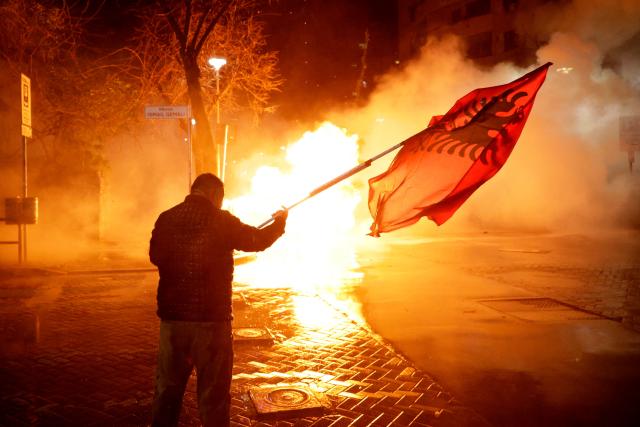 TOPSHOT - A man waves an Albanian flag as demonstrators clash with Albanian riot police during an anti-government protest in Tirana on February 28, 2026.  (Photo by Adnan Beci / AFP)