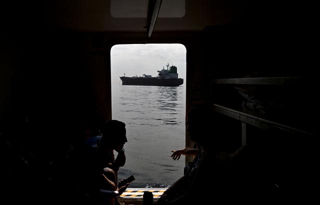 Tourists look at a cargo ship waiting to enter the Panama Canal in Panama City on February 28, 2026. (Photo by MARTIN BERNETTI / AFP)