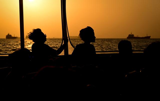 Tourists look at a cargo ship waiting to enter the Panama Canal in Panama City on February 28, 2026. (Photo by MARTIN BERNETTI / AFP)