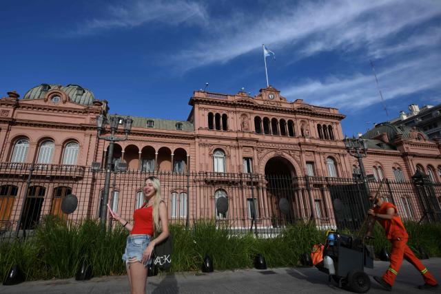 A woman takes a selfie in front of presidential palace Casa Rosada in Buenos Aires on February 28, 2026. Argentina went on high alert on February 28 after the US and Israeli attacks on Iran and the latter's retaliatory strikes. The heightened alert in Argentina involves "all the country's sensitive targets, critical infrastructure and the Jewish community," President Javier Milei's office said in a statement. (Photo by Luis ROBAYO / AFP)
