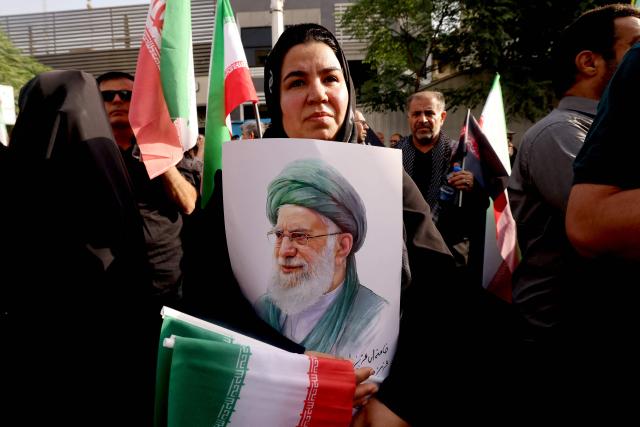 (FILES) A mourner holds up a poster showing the image of Iran's Supreme Leader Ali Khamenei during the funeral of the Iranian Revolutionary Guards commander and other military commanders killed in Israeli strikes on Iran, during their funeral procession at Enghelab (Revolution) Square in the capital Tehran on June 28, 2025. Iranian state television on March 1, 2026 confirmed the death of Iran's supreme leader Ayatollah Ali Khamenei, without referring to a massive US and Israeli attack on his residence. (Photo by ATTA KENARE / AFP)