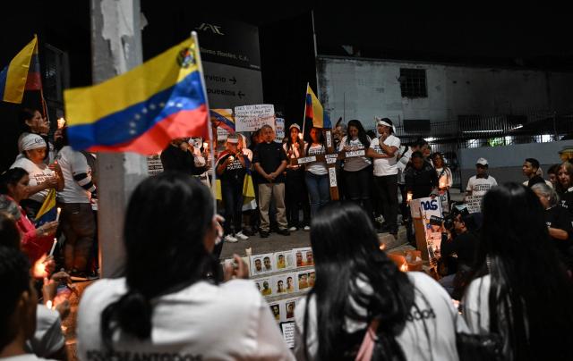 People hold a vigil to demand the release of political prisoners outside of Helicoide prision in Caracas on February 28, 2026. More than 500 political prisoners have been released as part of a liberation process promoted by interim president Delcy Rodriguez, who assumed power after the capture of Nicolas Maduro in a US military operation. (Photo by Juan BARRETO / AFP)