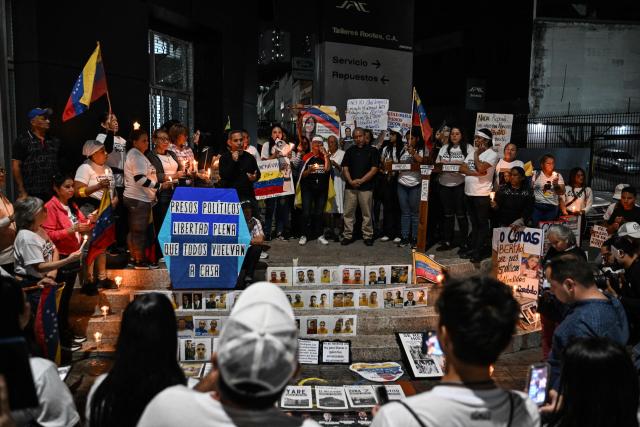 People hold a vigil to demand the release of political prisoners outside of Helicoide prision in Caracas on February 28, 2026. More than 500 political prisoners have been released as part of a liberation process promoted by interim president Delcy Rodriguez, who assumed power after the capture of Nicolas Maduro in a US military operation. (Photo by Juan BARRETO / AFP)