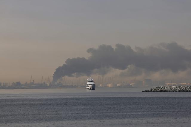 A yacht sails past a plume of smoke rising from the port of Jebel Ali following a reported Iranian strike in Dubai on March 1, 2026. Fresh blasts were heard across the Gulf cities of Dubai, Doha and Manama on Sunday morning after a day of Iran strikes in the region in retaliation for US and Israeli attacks. (Photo by Fadel SENNA / AFP)