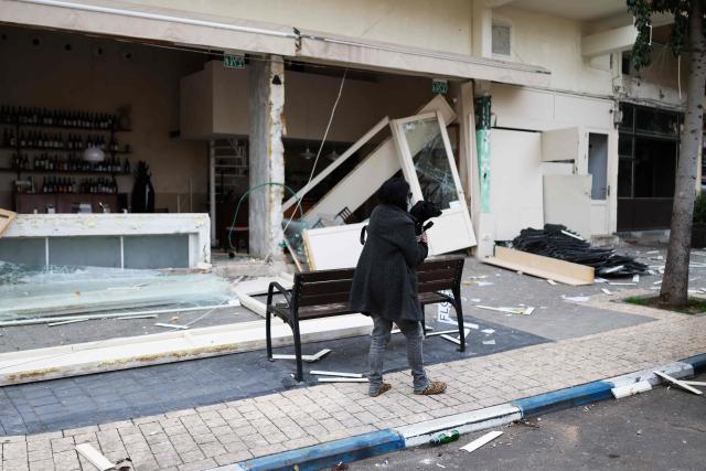 A woman walks past a store damaged in a reported overnight Iranian strike in Tel Aviv on March 1, 2026. US President Donald Trump said February 28 that Iran's supreme leader Ayatollah Ali Khamenei was dead, after Israel and the United States launched an attack of unprecedented scale aimed at bringing down the Islamic republic. (Photo by Ilia YEFIMOVICH / AFP)