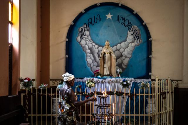 A worshipper lights a candle in front of an altar at the Saint Augustin d'Amoutieve parish in Lome on February 28, 2026. (Photo by OLYMPIA DE MAISMONT / AFP)