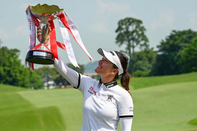 Hannah Green of Australia celebrates with the trophy after winning the HSBC Women’s World Championship at Sentosa Golf course in Singapore on March 1, 2026. (Photo by Roslan RAHMAN / AFP)