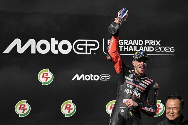 Winner Aprilia Racing's Italian rider Marco Bezzecchi celebrates on the podium as Thai Prime Minister Anutin Charnvirakul (R) looks on after the MotoGP Thailand Grand Prix at the Buriram International Circuit in Buriram on March 1, 2026. (Photo by Lillian SUWANRUMPHA / AFP)