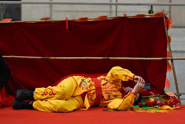 A dancer rests during a Chinese New Year performance of traditional dances at the plaza of the Museum of the Communist Party of China in Beijing on March 1, 2026, ahead of the opening of the annual session of the National People's Congress (NPC). (Photo by Pedro PARDO / AFP)