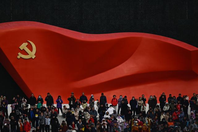 People watch a Chinese New Year performance of traditional Chinese dances with a sculptural flag of the Communist Party seen in the background at the plaza of the Museum of the Communist Party of China in Beijing on March 1, 2026, ahead of the opening of the annual session of the National People's Congress (NPC). (Photo by Pedro PARDO / AFP)